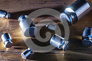 Set of small weights for jewelry scales on a wooden table. front and background blurred with bokeh effect