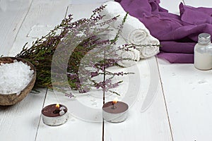 Set for spa treatments and heather branch lie on a white wooden table