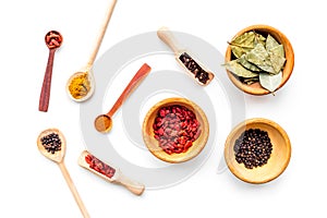 Set of spices for cooking. Scoops and spoons with spices, bowls with goji, bay leaf, pepper on white background top view