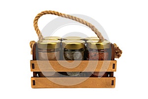 A set of spices in glass jars, packed in a wooden box with a rope handle