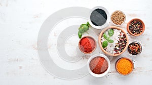 A set of Spices and herbs on a white wooden table. Basil, pepper, saffron, spices. Indian traditional cuisine.