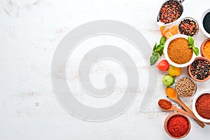 A set of Spices and herbs on a white wooden table. Basil, pepper, saffron, spices. Indian traditional cuisine.