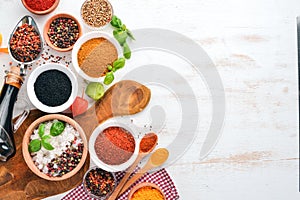 A set of Spices and herbs on a white wooden table. Basil, pepper, saffron, spices. Indian traditional cuisine.