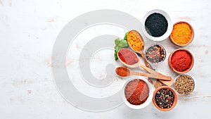 A set of Spices and herbs on a white wooden table. Basil, pepper, saffron, spices. Indian traditional cuisine.