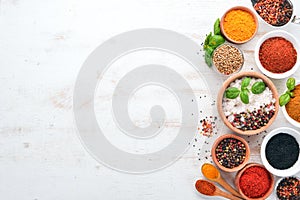 A set of Spices and herbs on a white wooden table. Basil, pepper, saffron, spices. Indian traditional cuisine.