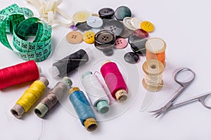 Set of spools of thread, scissors, buttons, fabrics and pins for sewing and needlework on a white background.