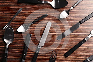 Set of spoons, forks and knives on wooden background