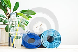 Set for sports, blue yoga mat towel and a bottle of water on a light background The concept of a healthy lifestyle Copy space