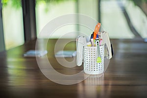 Set of stationaries in the plastic container on the wooden table