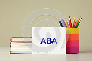 Set of stationery and card with abbreviation ABA Applied Behavior Analysis on wooden table against beige background