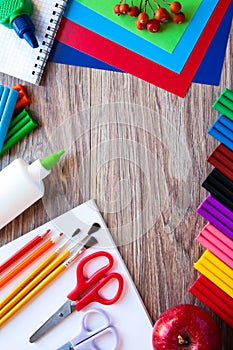 A set of stationery items on a wooden background. Colored paper, plasticine, and paints