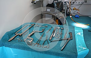 Set of steel surgical tools on blue cloth - real instruments used in mobile medical army tent, blurred operating table background