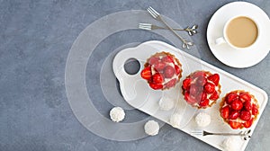 Set of strawberry tartlets or berry mini cakes with cup of coffee and candy