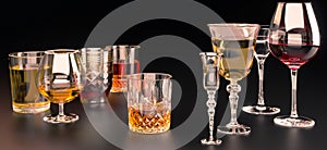 A set of strong alcoholic beverages in glasses, in the presence of whiskey, vodka, rum, brandy, tequila, on a dark background