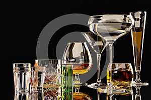 A set of strong alcoholic beverages in glasses, in the presence of whiskey, vodka, rum, brandy, tequila, on a dark background