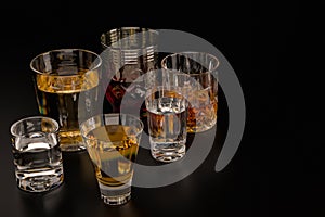 A set of strong alcoholic beverages in glasses, in the presence of whiskey, vodka, rum, brandy, tequila, on a dark background