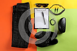 Set of stylish black women`s clothing, fashionable women`s accessories on a colorful background. flat lay