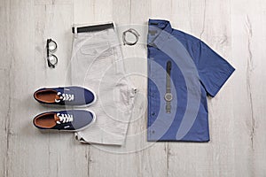 Set of stylish clothes and accessories on wooden floor