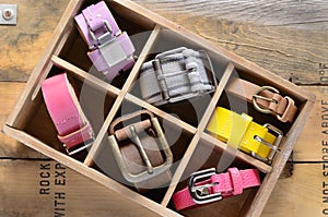 Set of stylish vintage belts in wooden crate