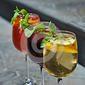 Set of summer refreshments on a stone background with copy space. three glasses of red, yellow and orange lemonade.