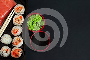 Set of sushi and maki with soy sauce over black stone background. Top view with copy space