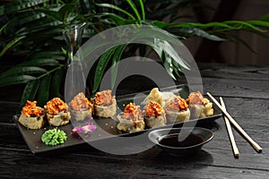 Set of sushi rolls on a black plate on a black wooden background