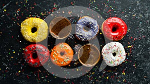 Set of sweet colored donuts with a cup of coffee on a black stone table