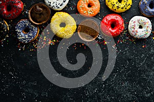 Set of sweet colored donuts with a cup of coffee on a black stone table.