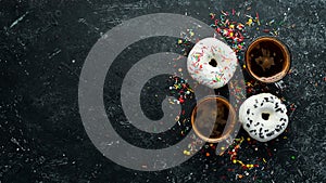 Set of sweet colored donuts with a cup of coffee on a black stone table.