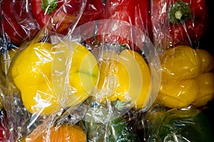 Set of sweet peppers of different colors from local market in plastic shopping bag. Top view. Organic food. Plastic Pollution,