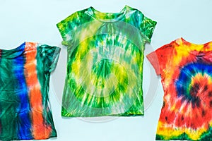 Set of t-shirts decorated in tie dye style on a light background. Flat lay.