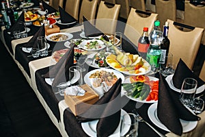 Set table with plates and dishes at the restaurant. Birthday party or wedding celebration at the cafe with different food. Black