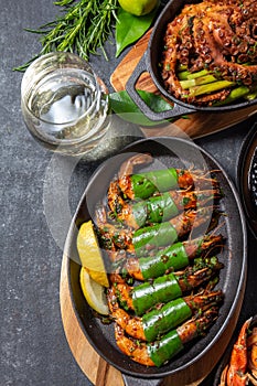 Set table with seafood dishes - cooked crabs, tiger shrimps, grilled octopus and squids on cast iron pan.