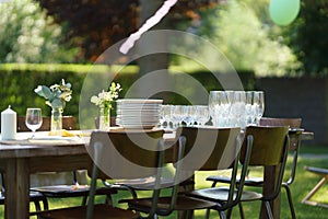 Set table at summer garden party, empty plates and glasses. Table setting with glasses, lemonade, delicate floral and