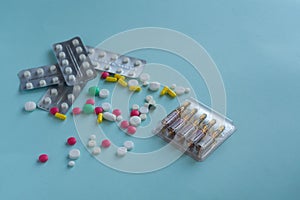 A set of tablets in packs, pills in blisters and ampoules on a blue background. Doctor Medical concept. White, yellow, pink