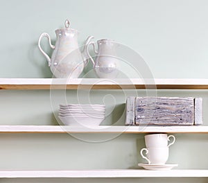 Set of tea cups and ceramic teapot on shelf