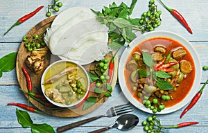 Set of Thai food green curry on soup bowl and red curry on plate with thai rice noodles vermicelli ingredient herb vegetable on