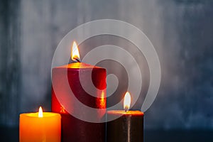 set of three autumn colored candles burning