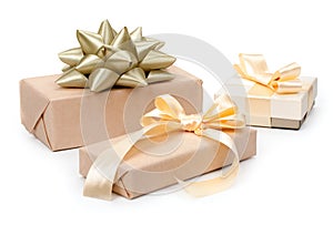 Set of three of gift boxes with presents wrapped in kraft paper and with golden light beige bow and gold bow isolated on the white