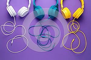 Set of three headphones over purple background. Music concept.