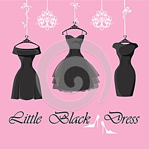 Set of three little black dresses hang on ribbons