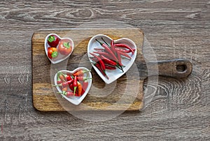 Set of three plates with hot pepper and chili on a wooden cutting board background top view