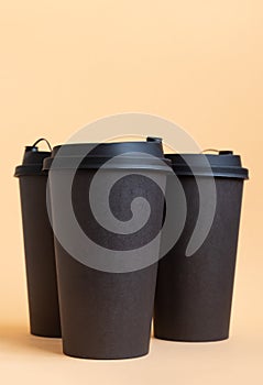 Set of three takeaway black coffee cup on neutral background natural light. Mock -up, nobody, front view, vertical