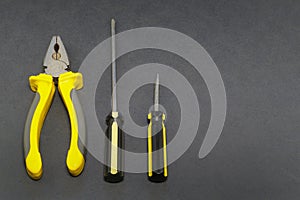 A set of tools on a gray background pliers, screwdriver