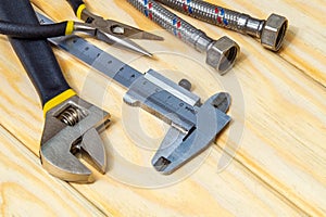 Set of tools and hose for plumbers on wooden boards with space for advertising photo