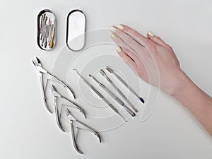 Set of tools for manicure and a female hand. White background