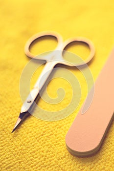 Set of tools for manicure. Scissors and nail file on the yellow table closeup