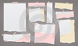 Set of torn white, pink and yellow note, notebook paper strips and pieces stuck with sticky tape on dark grey background