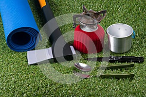 Set for tourist holiday items, rug, gas burner, green lawn background.
