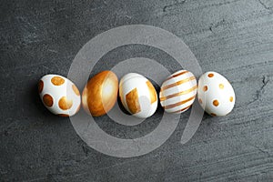 Set of traditional Easter eggs decorated with golden paint on grey background